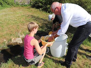 Ab in den Bach: G&uuml;nther Denzler und  Friedrich Schmauser setzen 1000 kleine Forellen in die Aufse&szlig; ein. Links  die Fischwirtin Alina Gro&szlig;mann von der Lehranstalt f&uuml;r Fischerei. Foto: Sabine Heid--