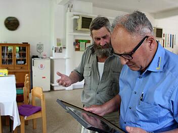 Vorsitzender Joachim Goebel und Kassier Herbert Hartmann schauen sich die alten Bilder des Vereins an. Viele sind gestorben, haben aus Altersgründen aufgehört oder sind weggezogen.  Foto: Julia Raab