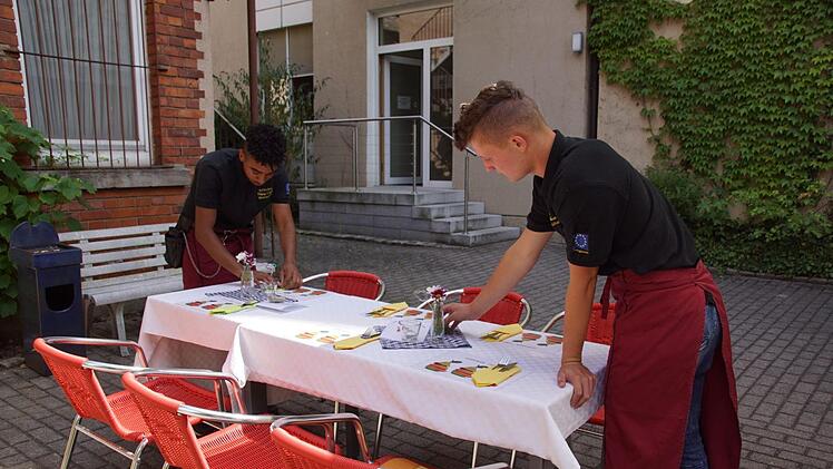 Gleich kommen die Gäste, Omar (links) und Marco decken den letzten Tisch. Foto: Sabine Weinbeer