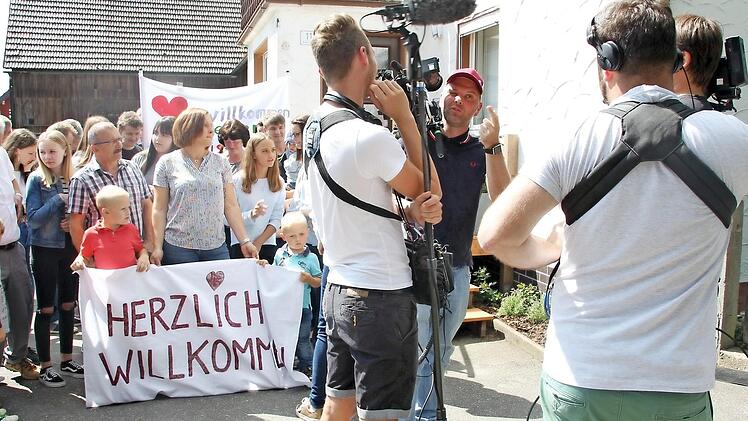 Besucher und Kamerateam warten auf die herannahende Familie.