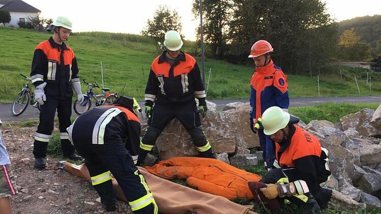 Die Rupbodner Floriansj&uuml;nger sind tatkr&auml;ftig bei der Sache, hier bei  einer &Uuml;bung mit  einer eingeklemmten Person (&Uuml;bungspuppe)  unter einem Felsstein.                                                Die "Person" wurde mit einfachen Mitteln befreit und im Anschluss ein Transport mit Krankentrage &uuml;ber schwieriges Gel&auml;nde ge&uuml;bt. Foto: Thomas H&uuml;fner