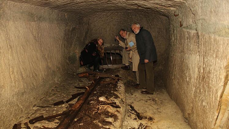 Pfarrerin Beate Stark, Thom Roessler und Peter Schuhmann schauen sich das Fenster auf dem Tablett an, das zum nächsten Keller führt. Foto: Michael Stelzner