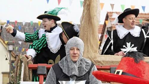 Ritter setzen beim Faschingszug auf einen motorisierten Wagen.