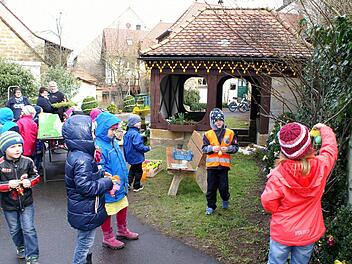 Vorschulkinder aus dem Rattelsdorfer Kindergarten schmücken auch bei wechselhaftem Wetter den Osterbrunnen. Foto: Renate Neubecker