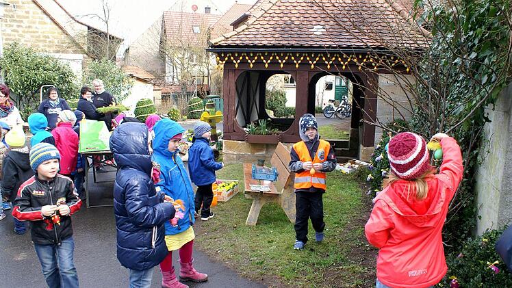 Vorschulkinder aus dem Rattelsdorfer Kindergarten schmücken auch bei wechselhaftem Wetter den Osterbrunnen. Foto: Renate Neubecker