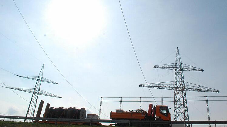 Der neue große Mast (rechts) bekommt jetzt seine Drähte, sein "Kollege" links wird überflüssig. Das Schutzgerüst sorgt dafür, dass beim Strippenziehen nichts auf die Maintalautobahn fallen kann. Fotos: Günter Flegek