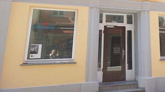 Helles Geb&auml;ude mit einem gro&szlig;en Fenster und Glast&uuml;r, gelbe Fassade, grauer Sockel. Es k&ouml;nnte sich um eine Bar in Bamberg handeln, &uuml;ber die Ger&uuml;chte kursieren, wie von inFranken.de berichtet.