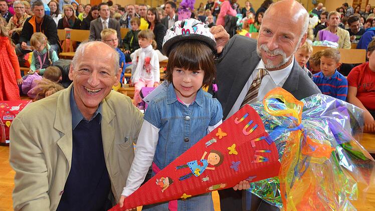 Julia, die am Donnerstag in der Henneberg-Grundschule eingeschult wurde, war eine von rund 160 Erstklässlern, die von Joachim Galuska (l.) und OB Kay Blankenburg (r.) einen Fahrradhelm bekam. Foto: Peter Rauch