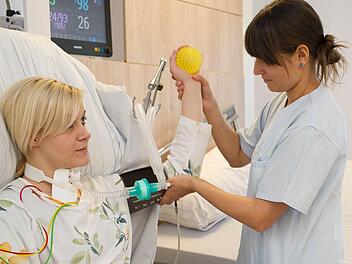 Auf diesem Bild führt Anna Schneider, Gesundheits- und Krankenpflegerin für Intensivpflege und Anästhesie, die Möglichkeit von ersten Rehabilitationsübungen auch bei beatmeten Patienten an ihrer Kollegin Vanessa Oechsner, Medizinische Fachkraft für Rehabilitation, vor. Fotos: Ralf Ruppert/Klinik Bavaria