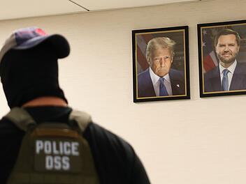 Ein New Yorker Bundesagent geht an Port&auml;rts von US-Pr&auml;sident Trum und Vizepr&auml;sident JD Vance vorbei. Die US-Regierung geht konsequent gegen Einwanderer ohne Aufenthaltstitel vor.