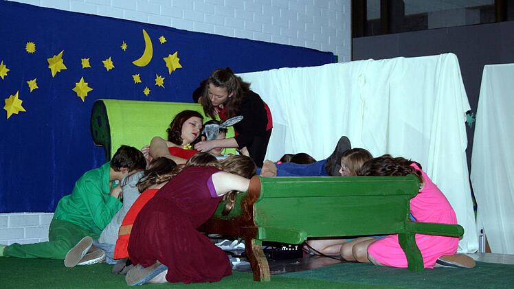 Oberon, König der Elfen (Lisa Kaufmann, stehend), legt Titania (Christin Hader) die Zauberblume aufs Gesicht.