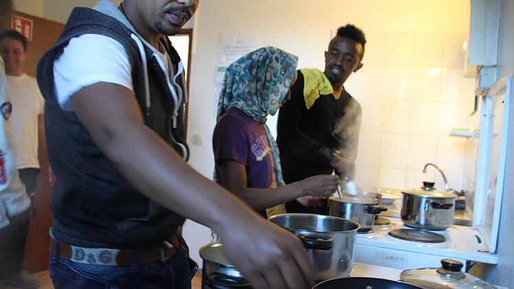 Eine junge, äthiopische Frau, die nicht genannt werden will, kocht zusammen mit Waleligne Zerga Degu (vorne) und Daniel Eliyas (beide aus Äthiopien) in der Gemeinschaftsküche der Unterkunft. Foto: Ulrike Müller
