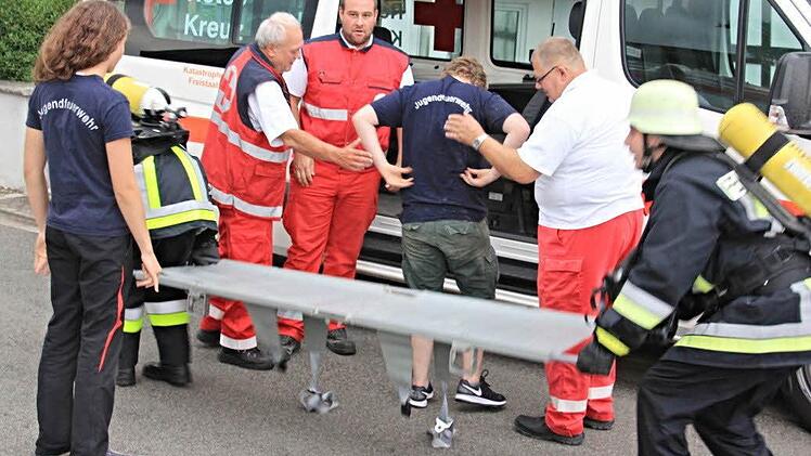 Mitarbeiter des BRK übernehmen von der Feuerwehr eine gerettete Person, um diese einer ärztlichen Versorgung zuzuführen.