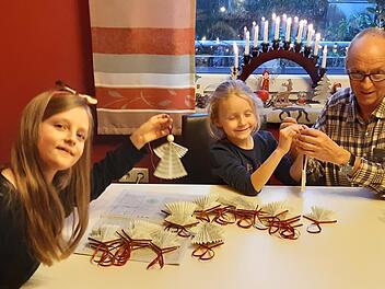 Hans Kober bastelt zusammen mit seinen Enkelinnen Helena  und Rosalie  Weihnachtsengel aus ausgedienten Gesangsbüchern.       Foto: Isabell Gerr