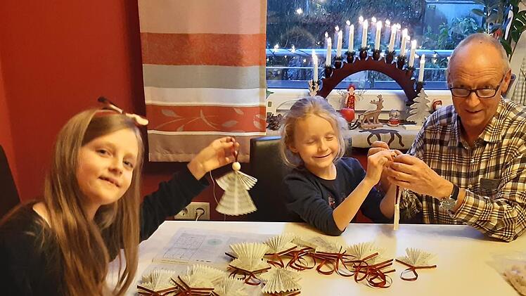 Hans Kober bastelt zusammen mit seinen Enkelinnen Helena  und Rosalie  Weihnachtsengel aus ausgedienten Gesangsbüchern.       Foto: Isabell Gerr