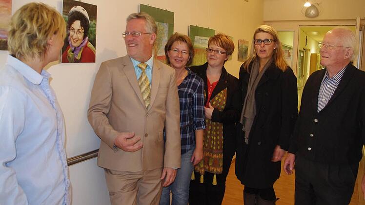 (von links) Pflegedienstleiterin Karin Büttner,  Helmut Weiß, Claudia Welsch, Katja Suffa-Weißkopf, Dagmar Alfsmann (Leiterin der Altenpflegeschule) sowie Heinrich Weiß bei der Vernissage. Das Bild (zwischen Karin Büttner und Helmut Weiß) zeigt die verstorbene Ilse Weiß, die die  Bilder gemalt hat.