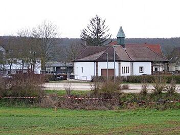 Der Friedhofsparkplatz mit den Spuren der aktuellen Vermessung, im Hintergrund das renovierte Leichenhaus. Nach einer Ortseinsicht am Friedhofsparkplatz beschloss der Gemeinderat, den dort vorhandenen Grenz&uuml;berbau eines Nachbargrundst&uuml;cks zu entfernen. Bei diesem R&uuml;ckbau sei die Entw&auml;sserung an der n&ouml;rdlichen Grenze festzulegen.  Foto: Adelheid Waschka