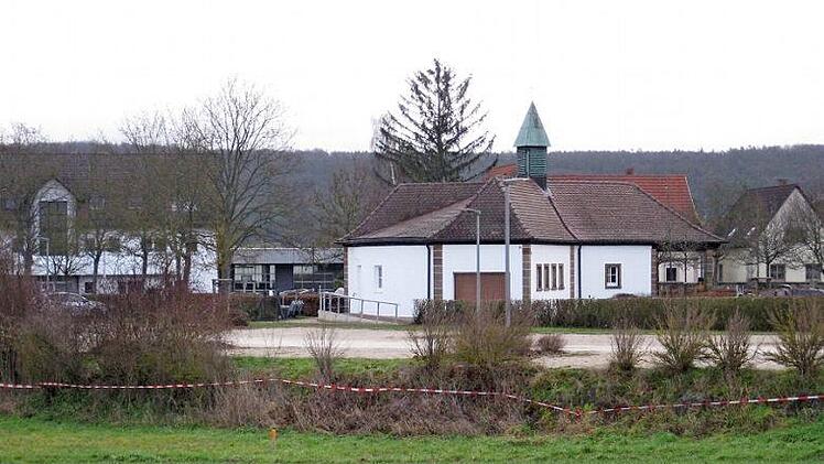 Der Friedhofsparkplatz mit den Spuren der aktuellen Vermessung, im Hintergrund das renovierte Leichenhaus. Nach einer Ortseinsicht am Friedhofsparkplatz beschloss der Gemeinderat, den dort vorhandenen Grenz&uuml;berbau eines Nachbargrundst&uuml;cks zu entfernen. Bei diesem R&uuml;ckbau sei die Entw&auml;sserung an der n&ouml;rdlichen Grenze festzulegen.  Foto: Adelheid Waschka