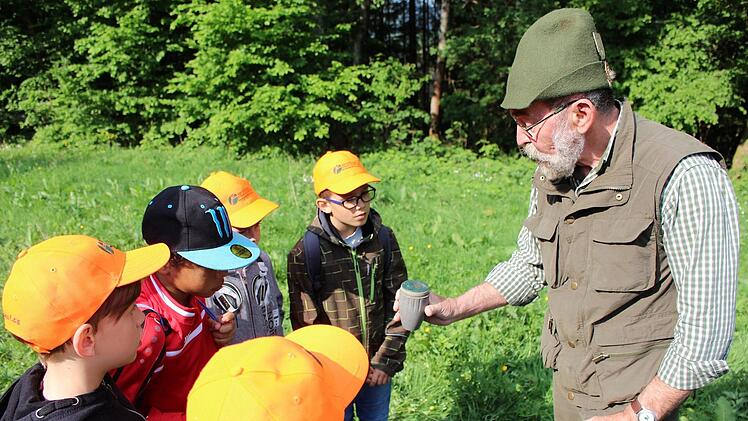 Gerd Gallitzdörfer zeigt den Kindern die Jagdtechnik bei der Kirrung mit spezieller Uhr und Jagdhandy