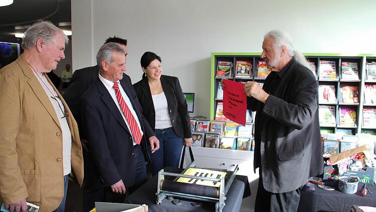 Die Prominenz beobachtet neugierig die Arbeit von Ingo Cesaro (rechts) an der Handpresse.  Foto: Mariell Dörrschmidt