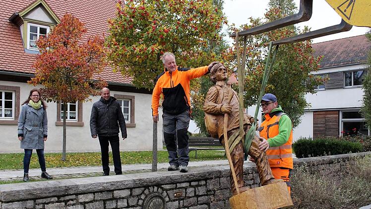 Karl-Heinz Weiner (links) und Simon Zink vom städtischen Bauhof bringen den Pilger an seinen Platz. Bürgermeister Johannes Krapp und zweite Bürgermeisterin Patricia Hanika verfolgen die Aktion. In der Mauer unterhalb ist der Jakobsbrunnen .Evi Seeger