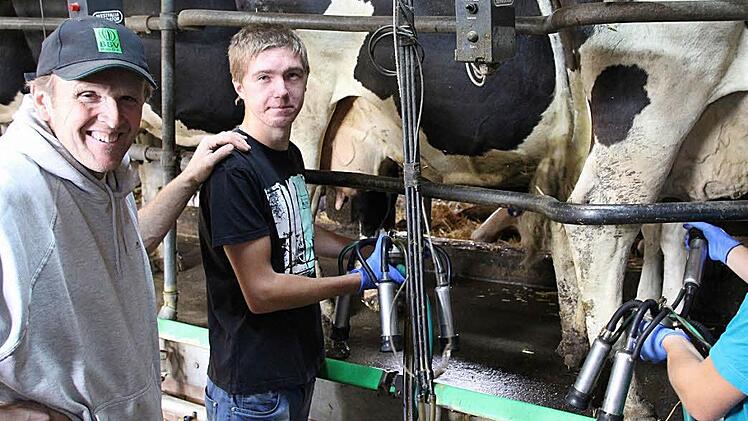 Herbert Kunick (links), Bio-Landwirt in Sonnefeld, mit den zwei russischen Praktikanten Fedor Raguzin (mitte) und Vladimir Nikulin beim Melken der Kühe  Foto: Christian Dreßel