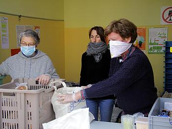 Mit Mundschutz und Handschuhen geben die Helfer der Tafel vorgepacke Lebensmitteltüten heraus. Foto: Bastian Reusch