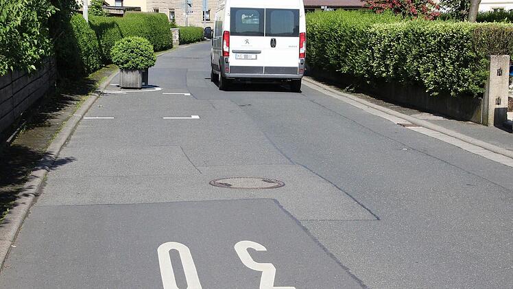 Mehrmals wird auf die Tempo-30-Zone hingewiesen. Auf beiden Straßenseiten sind wechselseitig Parkplätze ausgewiesen.