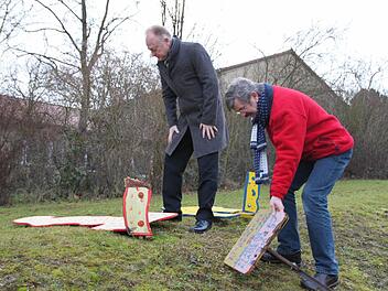 Bürgermeister Helmut Blank und Konrektor Michael Kübert (rechts) schauen sich die kaputten Holzskulpturen im Außenbereich der Freiherr-von-Lutz-Schule an. Es handelt sich um Schülerarbeiten aus dem Jahr 2007. Fotos : Heike Beudert