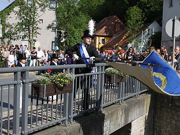 Der jüngste Stadtrat Sven Hofmann beim traditionellen Fahnenschwenken auf der Schwedenbrücke.  Foto: Michael Wunder