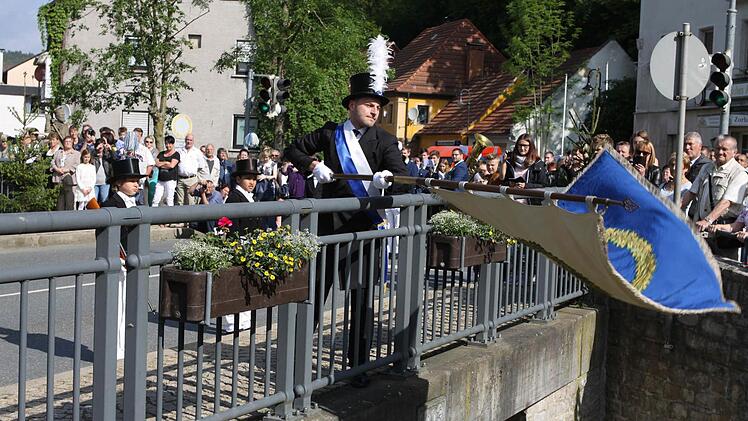 Der jüngste Stadtrat Sven Hofmann beim traditionellen Fahnenschwenken auf der Schwedenbrücke.  Foto: Michael Wunder