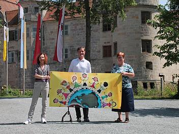 Vor dem Wasserschloss pr&auml;sentierte die Leiterin der Unicef-Arbeitsgruppe Oberfranken, Gisela Schardt, das Plakat f&uuml;r das 14. Unicef-Kinderfest in Mitwitz zusammen mit B&uuml;rgermeister Hans-Peter Laschka und Barbara Laschka (von links ). Foto: Herbert Fischer