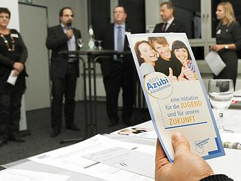 Jeder Unternehmer bekam Infomaterial zur Akademie. Im Hintergrund sind die Teilnehmer der Diskussionsrunde zu sehen.