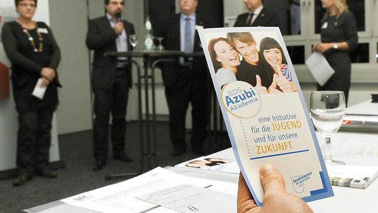 Jeder Unternehmer bekam Infomaterial zur Akademie. Im Hintergrund sind die Teilnehmer der Diskussionsrunde zu sehen.