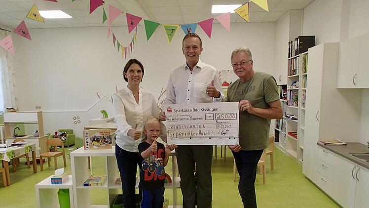 Leiterin des Poppenrother Kindergartens, Sabrina Metz (von links), nimmt von Christian Reuß und Klaus Rettinger den Spendenscheck entgegen. Mit auf dem Bild: der kleine Linus Reuß.Wolfgang Wimmel