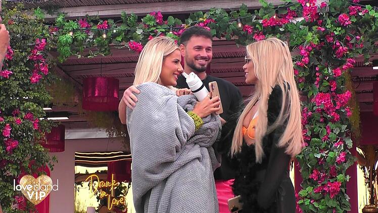 Maurice steht zwischen zwei sehr blonden Frauen.