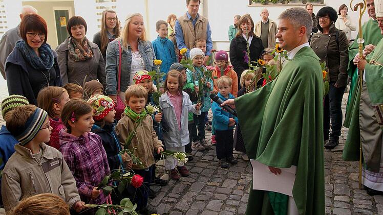 Mit Blumen und Liedern empfingen die Buben und Mädchen der Kindergärten St. Barbara und St. Josef den Bischof Friedhelm Hofmann (rechts). Vor den Kindern steht Stadtpfarrer Stephan Eschenbacher.