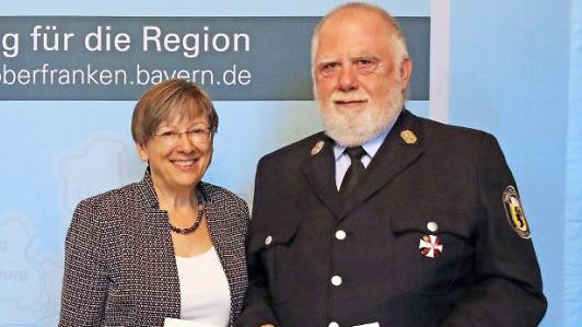 Regierungspräsidentin Heidrun Piwernetz hat Thomas Döll Ehrenurkunde und Steckkreuz ausgehändigt.  Foto: Michael Weiser, Regierung von Oberfranken