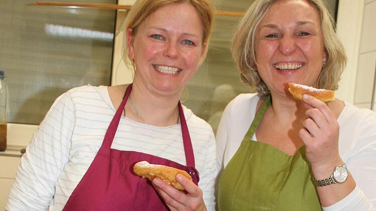 Kerstin Fischer und Kerstin Blumensaat probieren die Küchla noch warm. Foto: Sonny Adam