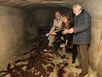 Diplom-Ingenieur Thom Roessler, Pfarrerin Beate Stark und Peter Schuhmann schauen sich die alten Eichenhölzer auf einem der Tabletts an, wo früher große Bierfässer gelagert wurden. Foto: Michael Stelzner