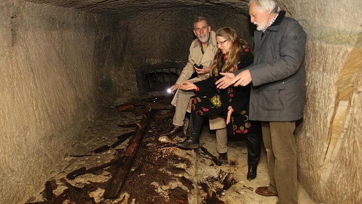 Diplom-Ingenieur Thom Roessler, Pfarrerin Beate Stark und Peter Schuhmann schauen sich die alten Eichenhölzer auf einem der Tabletts an, wo früher große Bierfässer gelagert wurden. Foto: Michael Stelzner