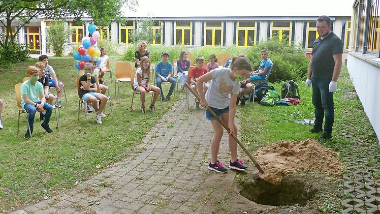 Jedes Kind aus der Klasse 4b griff zur Schaufel und bedeckte die beiden Kapseln mit Erde; hier ist Laura am Werk. Beobachter sind weitere Schüler der Grundschulklasse 4b und der Lehrer Tim Tropp.