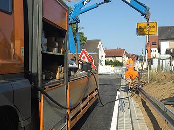 Rechts und links der Zufahrt zur Bahnbrücke bauen Fachkräfte noch Leitplanken ein. Foto: Stefan Geiger
