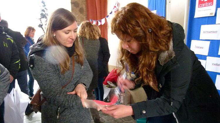 Maika Schneider (rechts) streicht Farbe auf die Handfläche einer Passantin. Foto: Marion Krüger-Hundrup