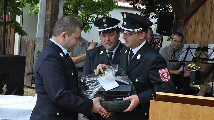 Für seine Bemühungen um den Kauf des Fahrzeugs erhielt Feuerwehrreferent Sebastian Bock (links) ein Präsent der anderen Art von Kommandant Stefan Betz (rechts) und dessen Stellvertreter Carsten Martin.Simon Albrecht