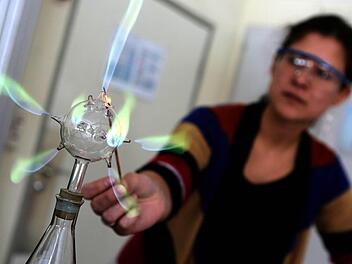 Chemielehrerin Lana Löser führt ihrer Klasse das "Tannenbaum"-Experiment vor: Der gasförmige Borsäuremethylester im Glas wird erhitzt und steigt als Gas auf. Dieses strömt aus dem Glaskolben und wird durch Anzünden sichtbar. Foto: Matthias Hoch