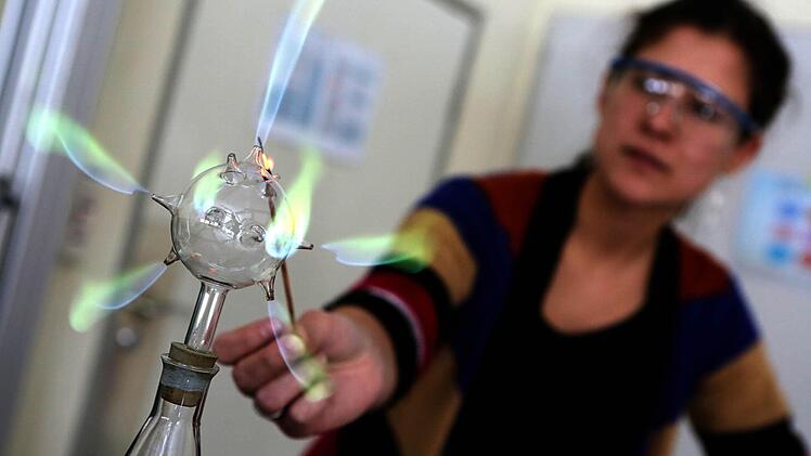 Chemielehrerin Lana Löser führt ihrer Klasse das "Tannenbaum"-Experiment vor: Der gasförmige Borsäuremethylester im Glas wird erhitzt und steigt als Gas auf. Dieses strömt aus dem Glaskolben und wird durch Anzünden sichtbar. Foto: Matthias Hoch