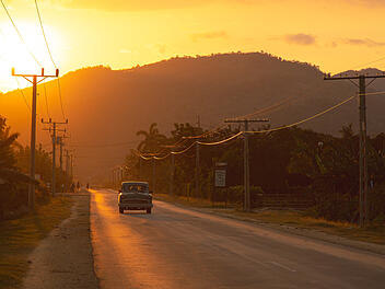 Ein klassischer kubanischer Oldtimer auf der Stra&szlig;e bei Sonnenuntergang in Chivirico, Kuba  von Anselm