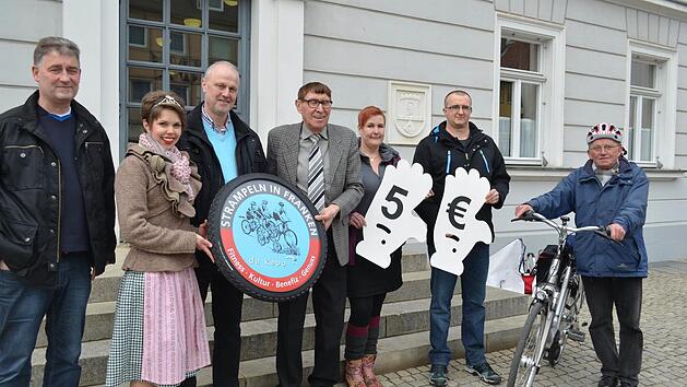 Dieter Maisel (Aral-Tankstelle), Katrin Uano, Gerald Brehm, Helmuth Schuh, Swenja Ott und Daniel Chmarra (Aral-Tankstelle) trafen auf dem Marktplatz Werner Geier (v. l.), der auf die kleine Versammlung aufmerksam wurde und in diesem Jahr unbedingt mitradeln will. Foto: Larissa H&auml;ndel