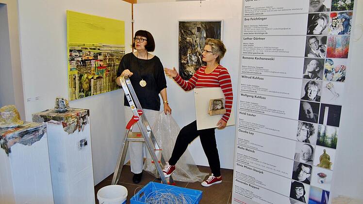 Die Bad Kissinger Künstlerinnen Silvia Pfister-Stanjek (links) und Eva Feichtinger beim Ausstellungsumbau vor Werken ihres Kollegen Alexander Ruppert. Foto: Sigismund von Dobschütz